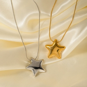 Detail view of 18K gold and silver star pendants on elegant champagne silk fabric