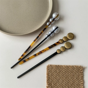 Minimalist hair pins with elegant pearls and tortoiseshell texture on ceramic plate
