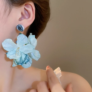 Detail of light blue fabric flower tassel earrings shown on a model for beach style