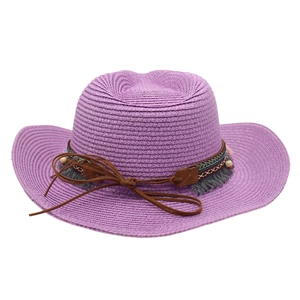 Purple woven cowboy straw hat with ethnic embroidery and tassel trim on white background