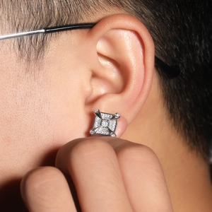 Macro shot of a silver dragon claw stud earring with square zircon on male model