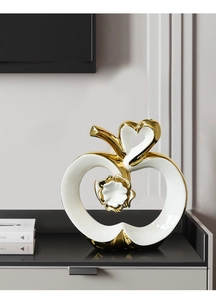 Detail of a ceramic apple ornament with hollow heart design and golden floral center
