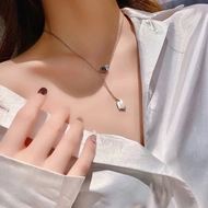 Close-up of a silver layered necklace featuring heart and geometric rectangle pendants