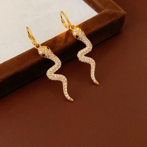 Detailed macro view of gold-plated snake earrings with sparkling clear zircon and black eyes