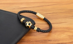 Detailed view of black braided leather bracelet featuring golden football bead and magnetic clasp