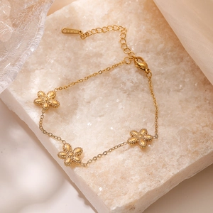 Elegant 18K gold plated four-leaf clover chain bracelet on a textured stone background