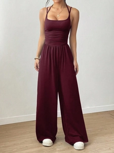 Women's burgundy halter neck wide leg jumpsuit with cinched waist and pleated detail