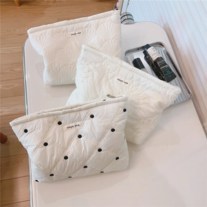 Detail of white quilted cosmetic bags with lace borders and 'simple wish' embroidery