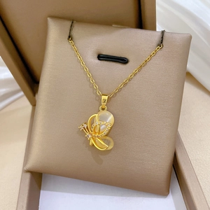 Close-up of golden butterfly pendant with white crystals and yellow cat-eye stone on silk