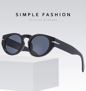 Detail of black round frame sunglasses featuring a silver arrow metal accent on the hinge