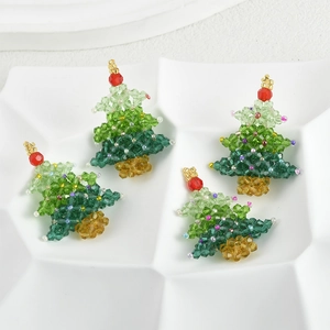 Detailed view of four handmade crystal beaded Christmas tree charms on a white tray