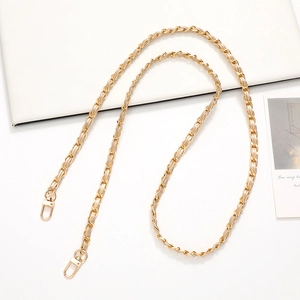 Detail of a gold metal chain interwoven with beige leather and secure lobster clasps