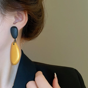 Close-up of model wearing irregular oval water drop wood earrings in black and yellow
