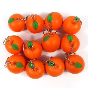 Macro shot of twelve mini realistic orange fruit keychains with green leaf details