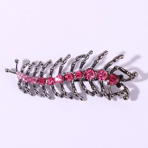 Détail de la broche mille-pattes en métal noir avec strass roses et yeux en cristal