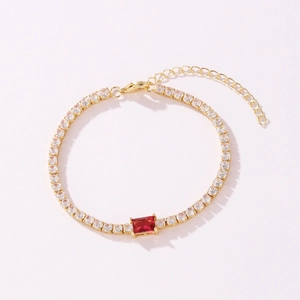 Detail of gold tennis bracelet with clear CZ and central red rectangular gemstone