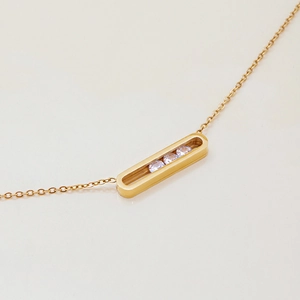 Detail of gold titanium steel necklace with rectangular pendant and three clear gemstones
