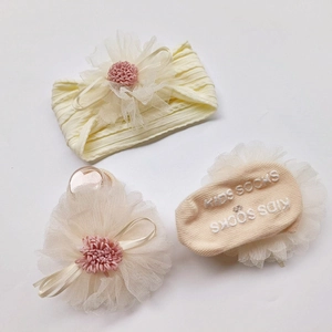 Detail of cream baby headband and socks set featuring large lace chiffon flowers