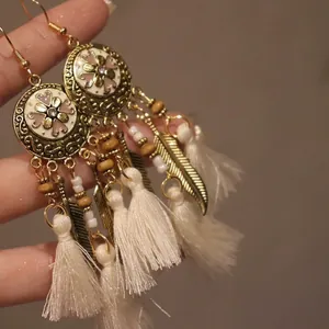 Detail of ethnic tassel earrings with antique gold carving and bohemian cotton fringe