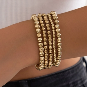 Stackable gold beaded bracelet set with heart pendant in minimalist metallic design