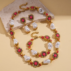 Vintage gold necklace set with baroque pearls and pink crystals on stone background