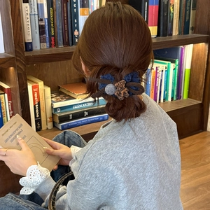 Retro bow hair tie with blue denim and leopard pattern on dark hair in library setting