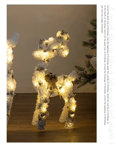 Close-up of lighted Christmas reindeer with white flocking and golden bow decoration