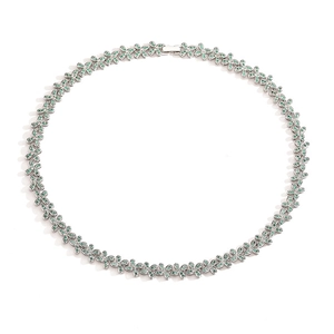 Detailed view of a silver necklace featuring green gemstones in a floral leaf pattern