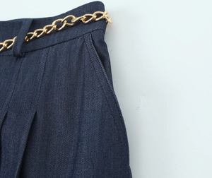 Gros plan détaillé d'un short en sergé bleu foncé avec ceinture chaîne dorée décorative