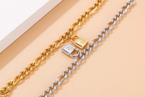 Nahaufnahme der mattierten Gold- und Silberketten-Armbänder mit Vorhängeschloss-Anhänger