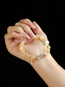 Macro shot of gold rutilated quartz and pink crystal beaded bracelet with Fu charm