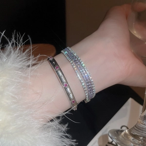Nahaufnahme von geschichteten Silberarmbändern mit roten Steinen und funkelnden Zirkonia
