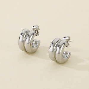 Macro detail of silver double-layered C-shaped stainless steel earrings with glossy finish
