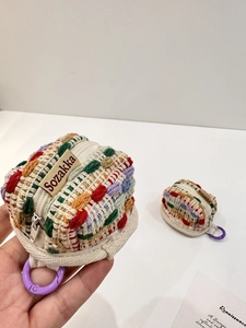 Close-up of handmade woven mini pouch for Airpods with colorful knit blocks and carabiner