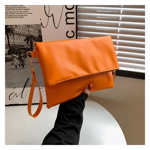 Dettagli di una borsa pochette arancione in ecopelle con cerniera dorata e cinturino