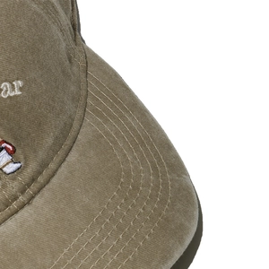 Macro shot of olive green washed cotton baseball cap with detailed bear embroidery