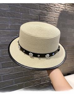 Close-up of fine woven straw hat texture with pearl floral and silver stud details