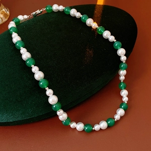 Dettaglio della collana vintage con perle e agata verde su base di velluto scuro