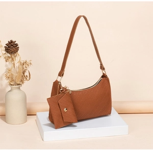 Close-up of brown underarm bag set with herringbone texture on a white pedestal