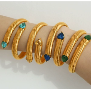 Close-up of gold snake-coil bracelets featuring teardrop colorful crystal end caps