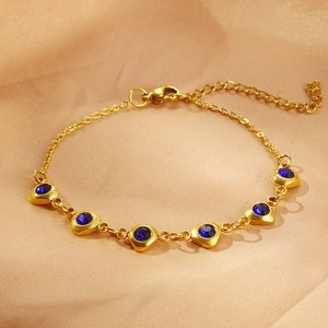 Detail of a gold stainless steel bracelet with blue heart-shaped zircons on champagne satin