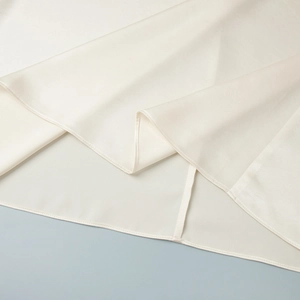 Detailed close-up of smooth satin dress hem with premium stitching and silky cream finish