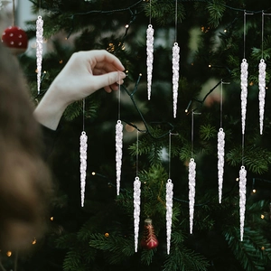 Close-up of clear acrylic Christmas icicle ornaments hanging on a festive pine tree branch