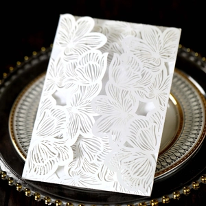 Detailed laser-cut floral pattern on white wedding invitation card with elegant texture