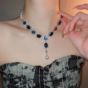 Détail du collier avec pierres bleu foncé et pendentif en perle en forme de goutte