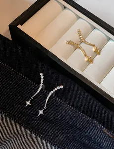 Close-up of elegant star pendant earrings in gold and silver plating with zircon