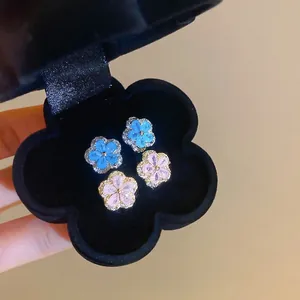 Luxury zircon flower stud earrings in light blue and pink on black velvet display
