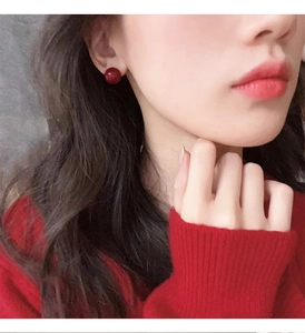 Close-up of elegant red spherical stud earrings worn by a model in casual attire