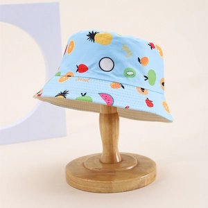 Close-up of light blue kids sun hat with colorful fruit patterns on a wooden stand