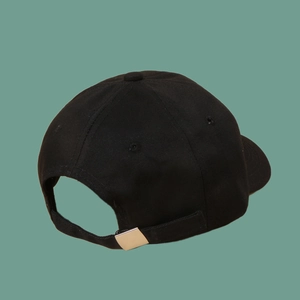 Detail of black cotton baseball cap showing adjustable silver metal buckle and stitching